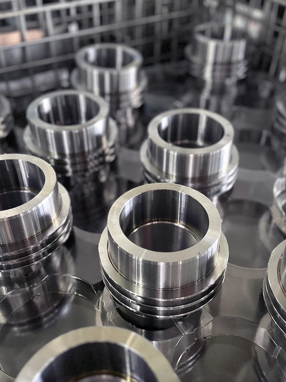A close-up, high-angle view of multiple polished, circular metal parts arranged in a grid within an industrial tray.